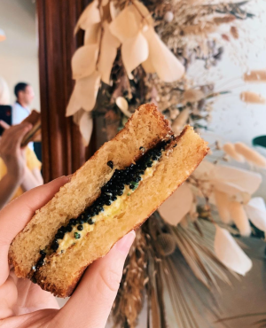 a hand holding a caviar sandwich