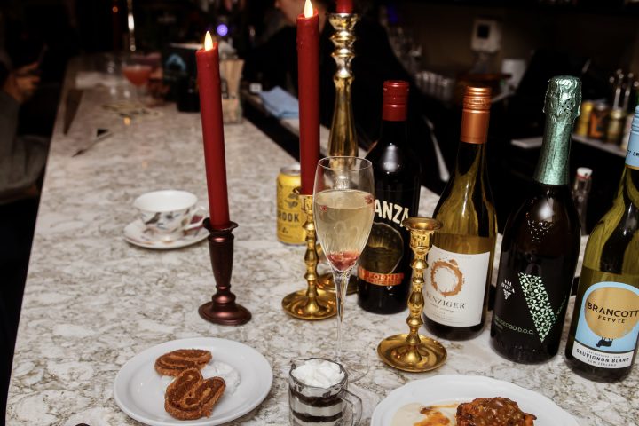 Bar with wine bottles, candles, and dessert plates on a marble counter.