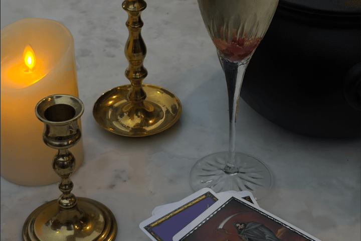 Tarot cards, candle, candlesticks, and champagne on a table.
