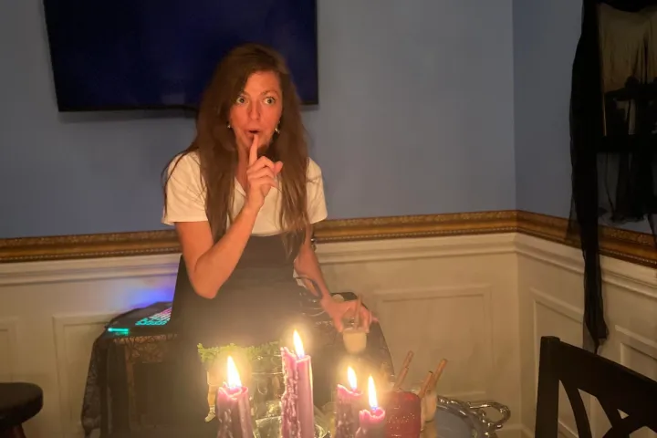 a woman sitting at a table with a birthday cake with lit candles