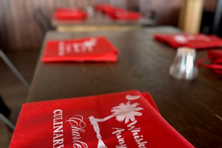 Red napkin on wooden table with 'Charleston Culinary Tours' printed in white.