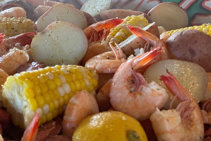 Close-up of a seafood boil with shrimp, corn, potatoes, and sausage.